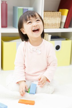 Asyalı Çinli küçük kız evde oyuncaklarla oynuyor.