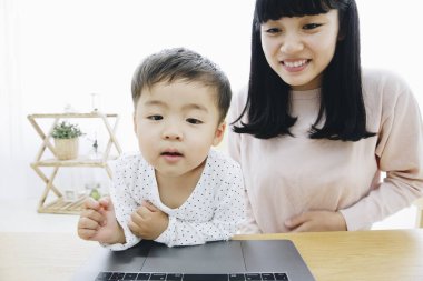 Asyalı anne ve oğlu bilgisayarda oynuyor.