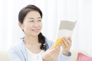 Mutlu Asyalı kadın kitap okuyor.