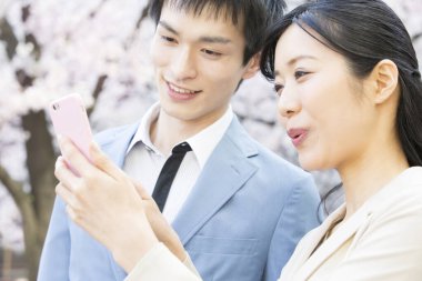 Parkta çiçek açan sakura ağaçları olan genç Asyalı çift.