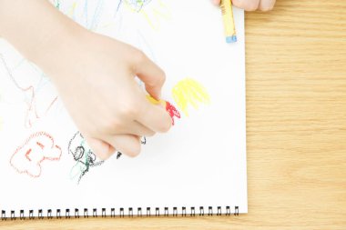 Renkli kalemlerle çizen çocuk elleri