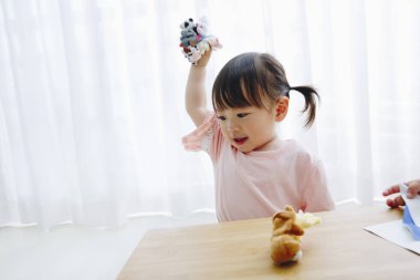 Küçük tatlı Japon kız oturma odasında oyuncaklarla oynuyor.