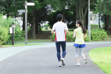 Sportif genç Asyalı çift parkta koşuyor.