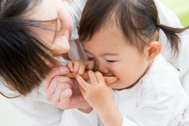 Evdeki oturma odasında genç annesiyle oynayan tatlı bir Japon kızı.