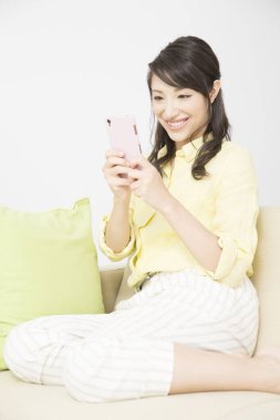 Evde akıllı telefon kullanan bir kadın. 