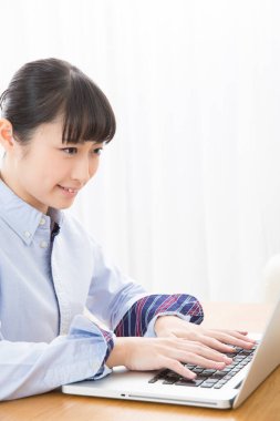 Genç Asyalı kadın evde bilgisayar kullanıyor.