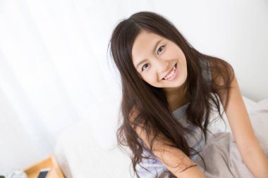 Yatak odasında gülümseyen güzel bir kadın portresi.