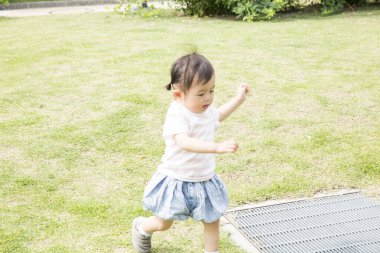 Parkta çimenlerde oynayan Asyalı kız 
