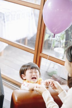 Mor balonu içeride tutan ağlayan çocuk.