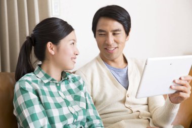 Genç Asyalı çift evde tablet bilgisayar kullanıyor.