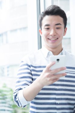 Genç mutlu adam akıllı telefon kullanıyor.