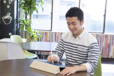 Genç Asyalı adam çizim için dijital tablet kullanıyor 