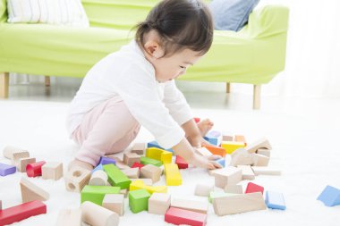 Küçük çocuk evde tahta bloklarla oynuyor.