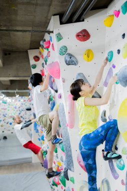 Spor salonundaki Asyalı gençler duvara tırmanıyor. 