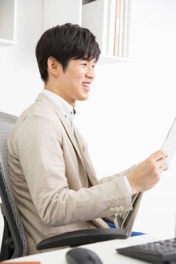 Genç adam ofiste gazete okuyor.