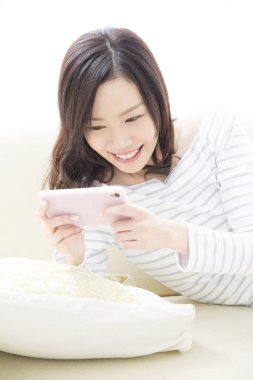 Güzel Asyalı kadın evde akıllı telefon kullanıyor.