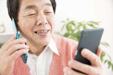 Usta Asyalı adam cep telefonu ve akıllı telefon kullanıyor. 