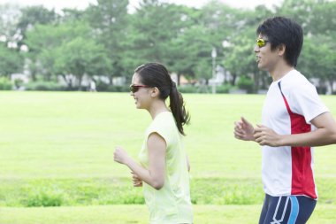 Sportif genç Asyalı çift parkta koşuyor.