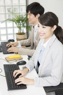 Genç Asyalı iş adamları ofiste bilgisayarlarla çalışıyorlar..