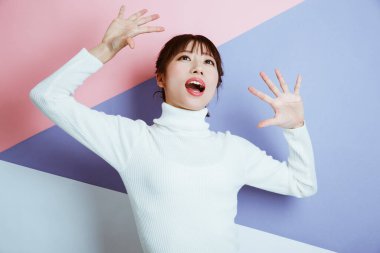 Stüdyoda ellerini kaldırıp poz veren Asyalı kadın. 