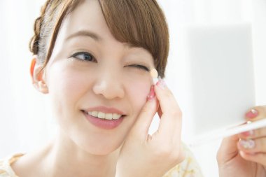 Genç Asyalı kadın göz makyajı yapıyor.