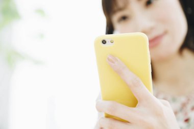 Akıllı telefonu elinde tutan genç bir kadın, akıllı telefon kullanıyor.