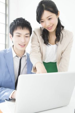 Genç Japon iş adamları ofiste dizüstü bilgisayarla çalışıyorlar.