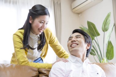 Kocasının boynuna masaj yapan genç bir kadın. 