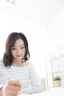 Genç Asyalı öğrenci not defterine yazıyor.