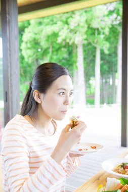 Kafede sandviç yiyen bir kadın.