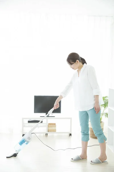 若いアジアの女性は家事をする 掃除機のリビングルームを掃除する日本の主婦 — ストック写真