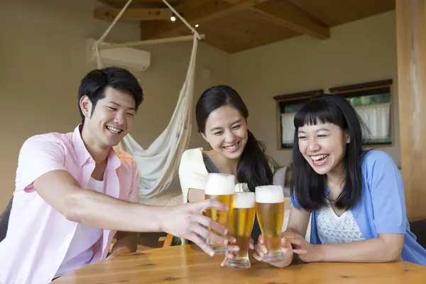 Smiling Asian friends drinking beer at hotel room during vacation