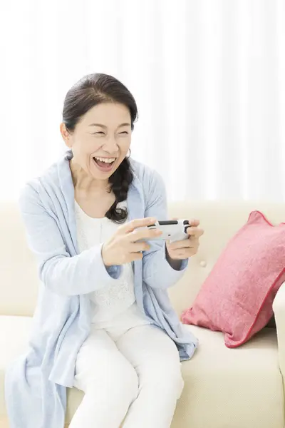 快乐的女人在家里沙发上玩电子游戏 — 图库照片