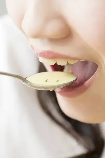 年轻的亚洲女人在用勺子喝汤 — 图库照片