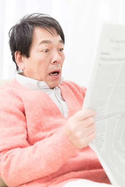 confused senior man reading newspaper