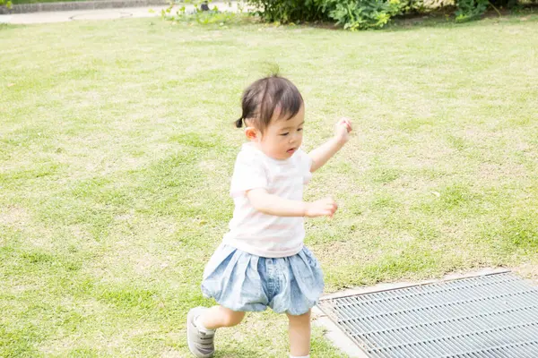 Parkta çimenlerde oynayan Asyalı kız 