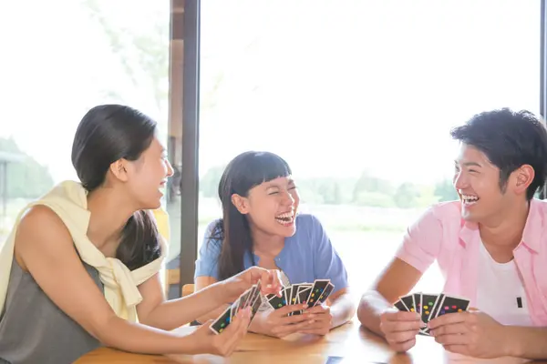 Bir grup genç arkadaş tatilde kulübede kart oynuyorlar.