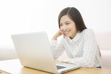 Masada dizüstü bilgisayar kullanan genç Asyalı kadın. 