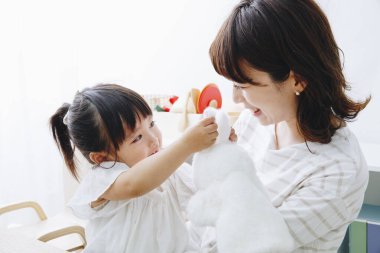 Aile fotoğrafı. Asyalı anne ve küçük kızı birlikte vakit geçiriyorlar. 