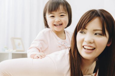 Asyalı genç kadın bebeğiyle oynuyor.