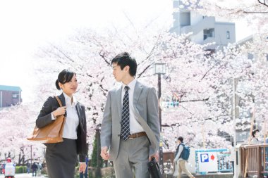 Şehir caddesinde kiraz çiçekleri olan iki Japon iş adamı.