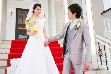 Merdivenlerde poz veren mutlu Asyalı gelin ve damadın portresi.