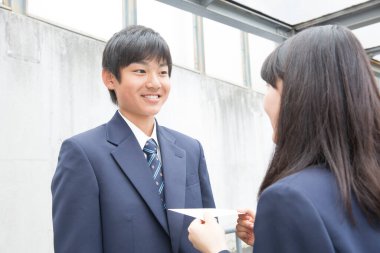 Gülümseyen öğrenciler okul üniformalarıyla mektuplaşıyorlar.