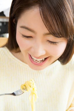 Genç bir kadın erişte yiyor.