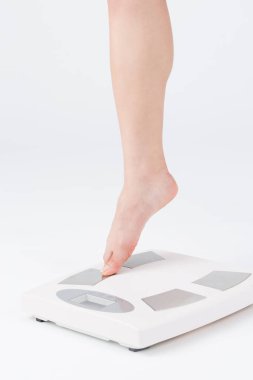 Kadın bacakları zemin terazisine basıyor, yakın plan. Terazinin üzerinde duran çıplak kadın, beyaz arkaplan