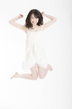 Beyaz elbiseli genç mutlu Asyalı kız atlıyor.