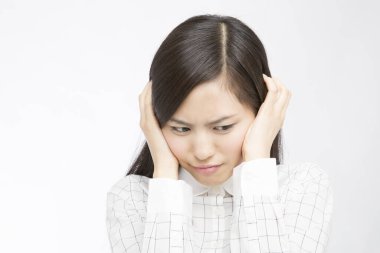 Beyaz arka planda elleri başının üstünde güzel, mutsuz Japon bir kadının stüdyo fotoğrafı. 