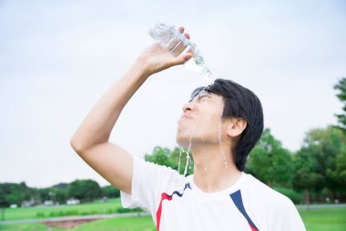 Asyalı adam parkta üzerine su döktü.