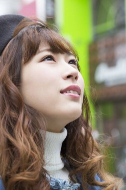 Güzel Asyalı genç kadın sokakta poz veriyor.