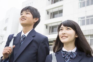 Modern okul binasının önünde yürüyen gülümseyen öğrenciler